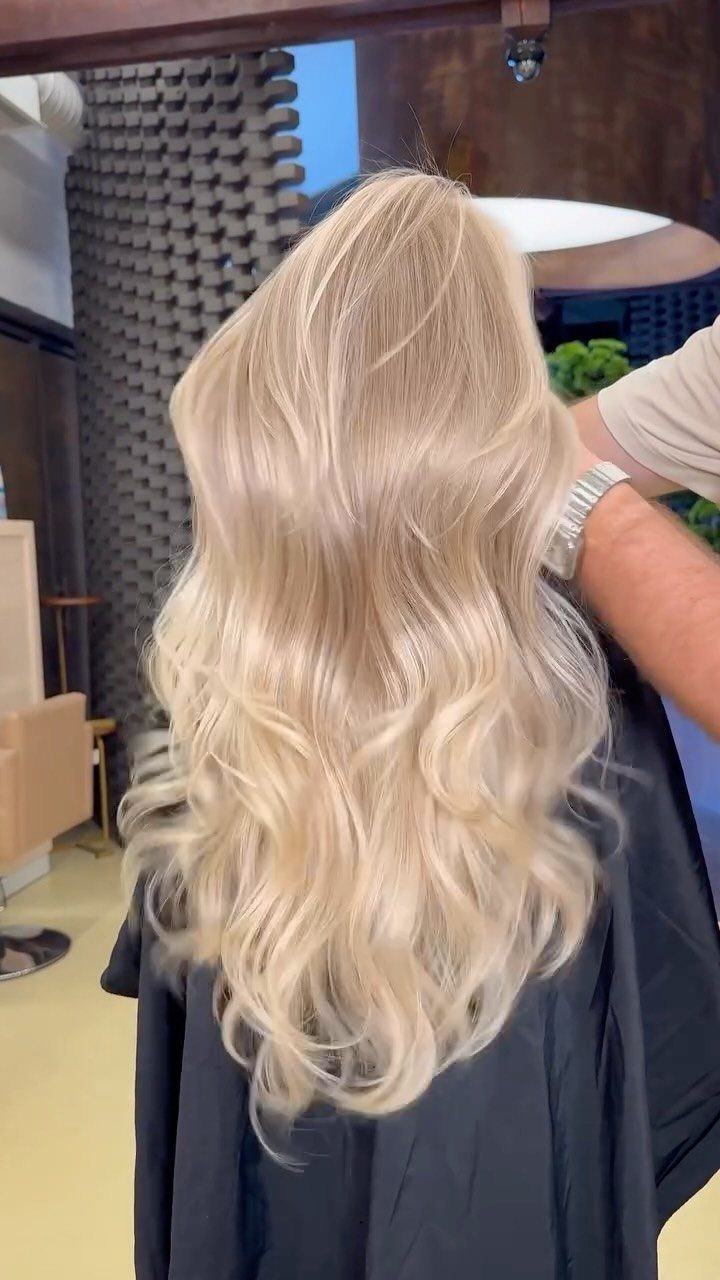 Long, wavy pale blonde hair with warm buttery tones in a salon