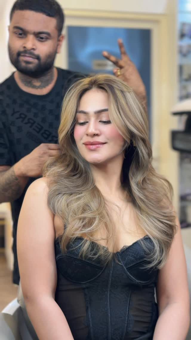 Woman with long, wavy cool beige-blonde hair seated in a salon chair