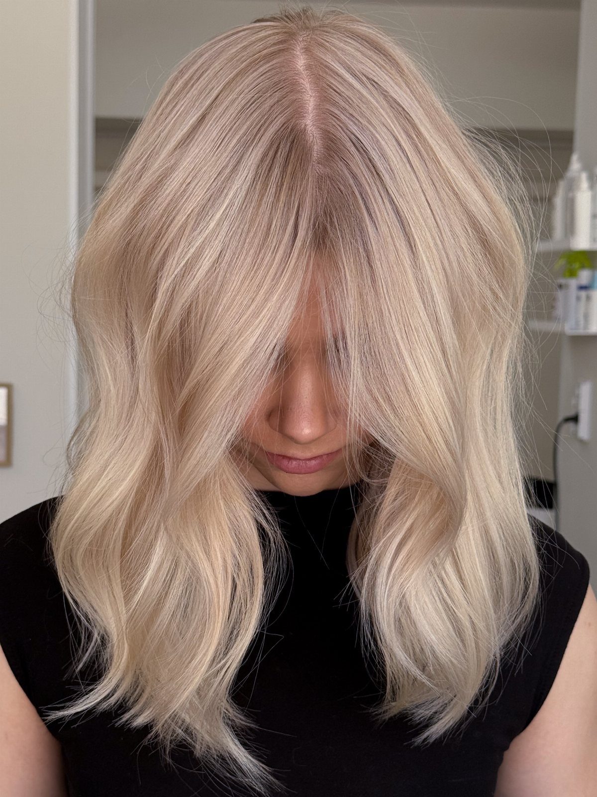 Pale blonde hair falls in soft waves around a woman’s face and shoulders
