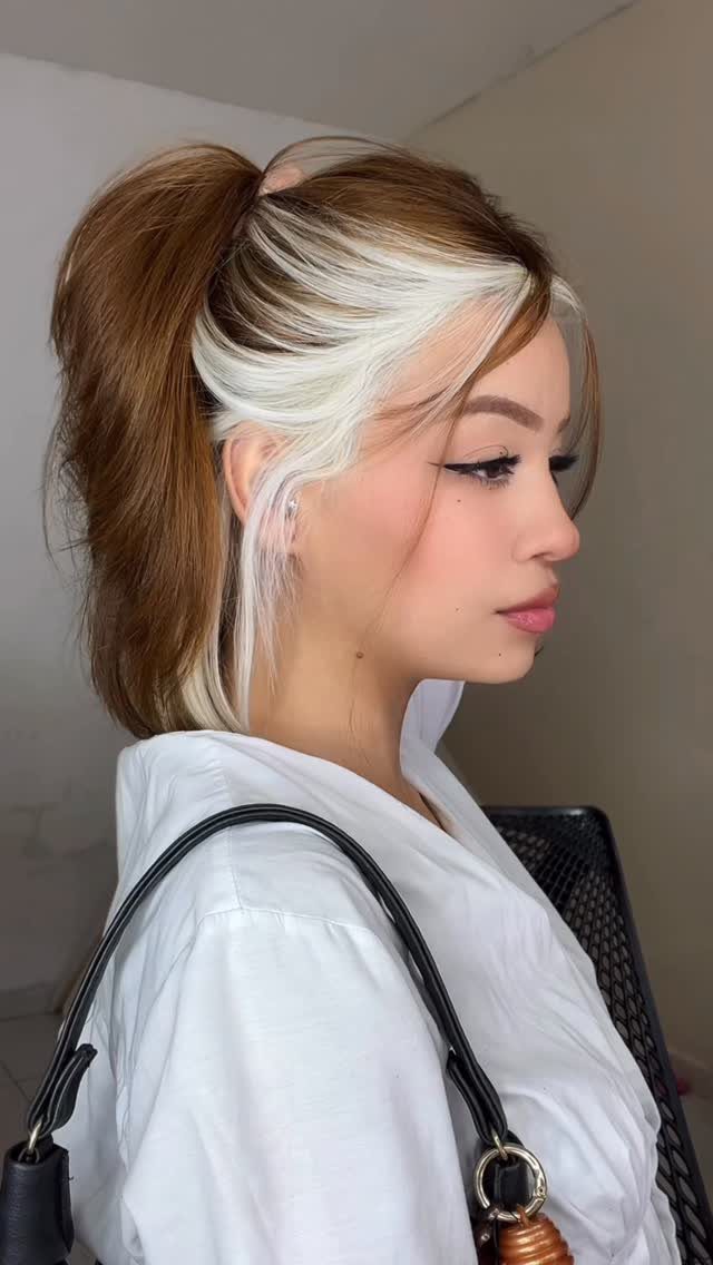 Woman with a brown ponytail and striking platinum-blonde front sections