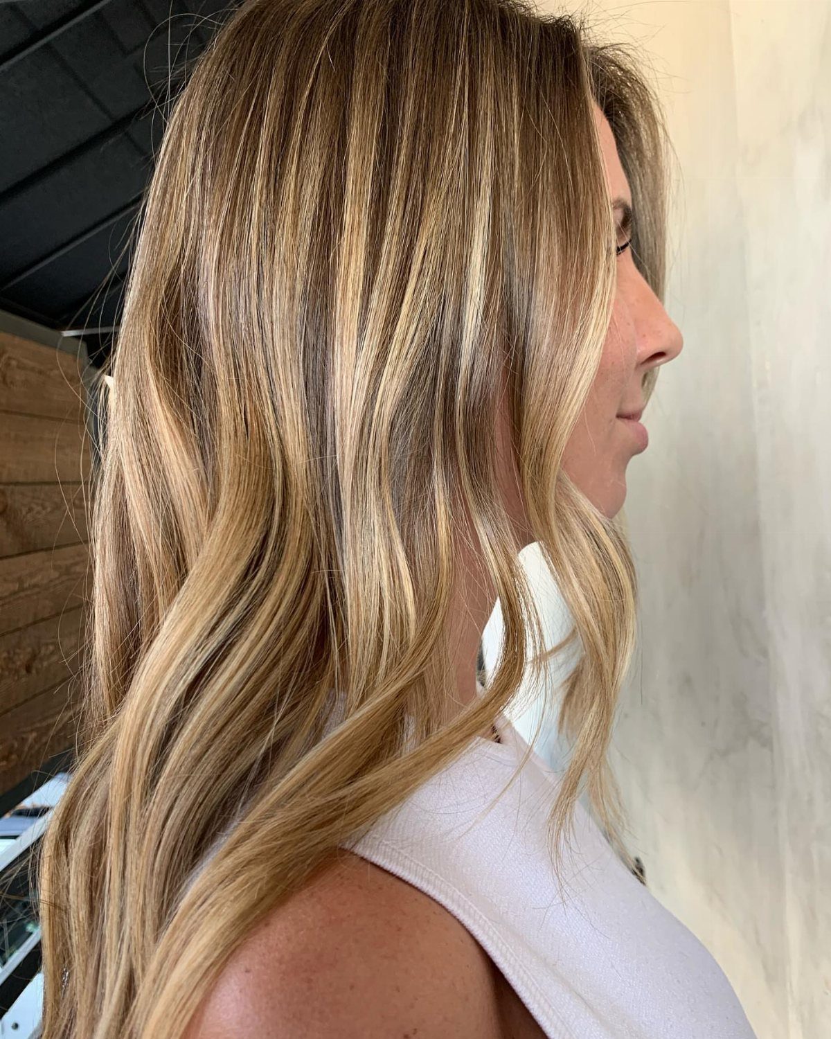 Long layered hair blends light brown roots with warm honey and creamy blonde highlights