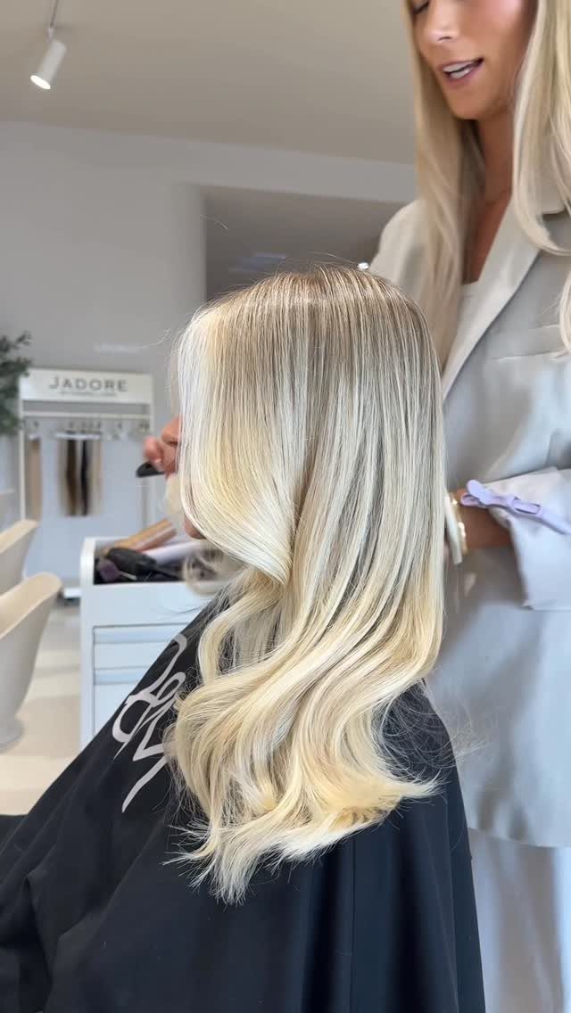 Long creamy blonde hair with cool pale tones styled in loose waves at a salon