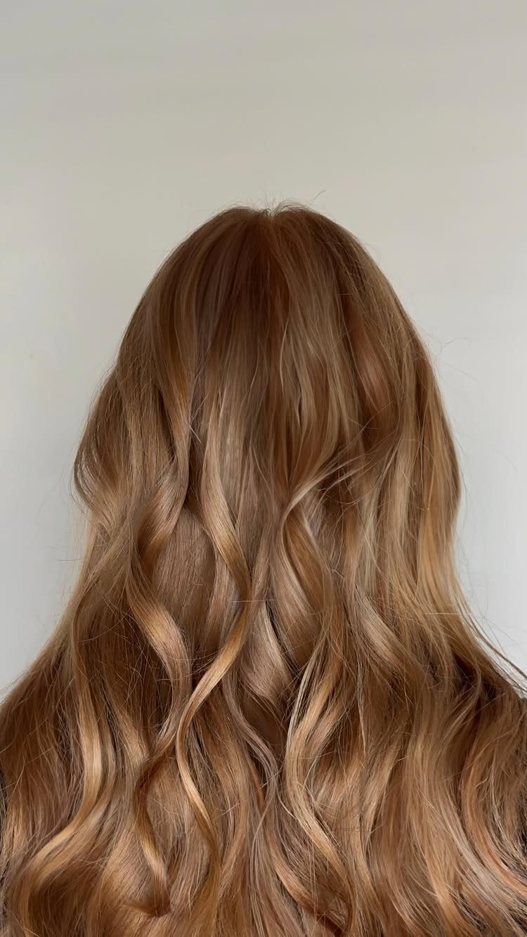 Long wavy blonde hair shows natural-looking depth, darker roots, and warm beige highlights