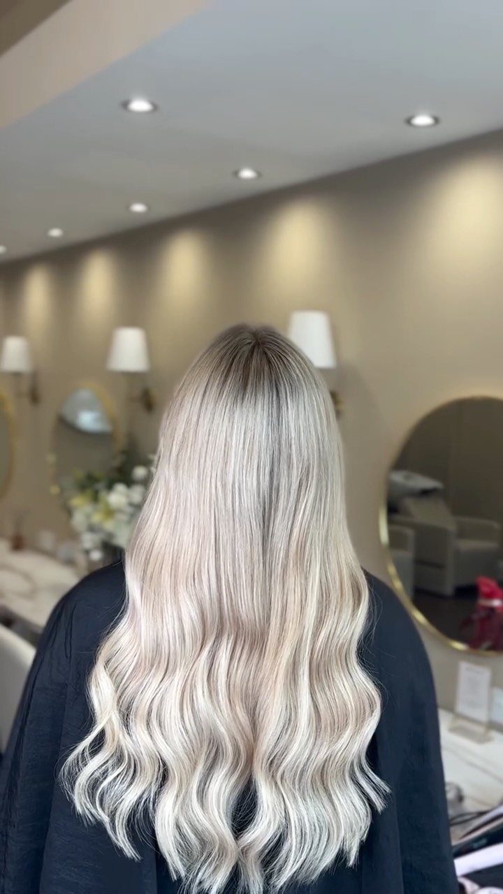 Long platinum blonde hair falls in loose waves down the back in a salon.