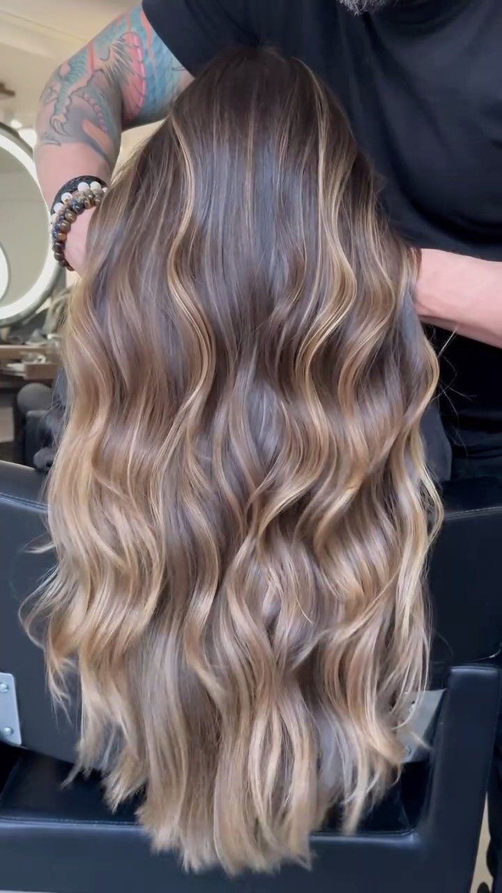 Long ash-brown hair with blonde tones styled in loose waves