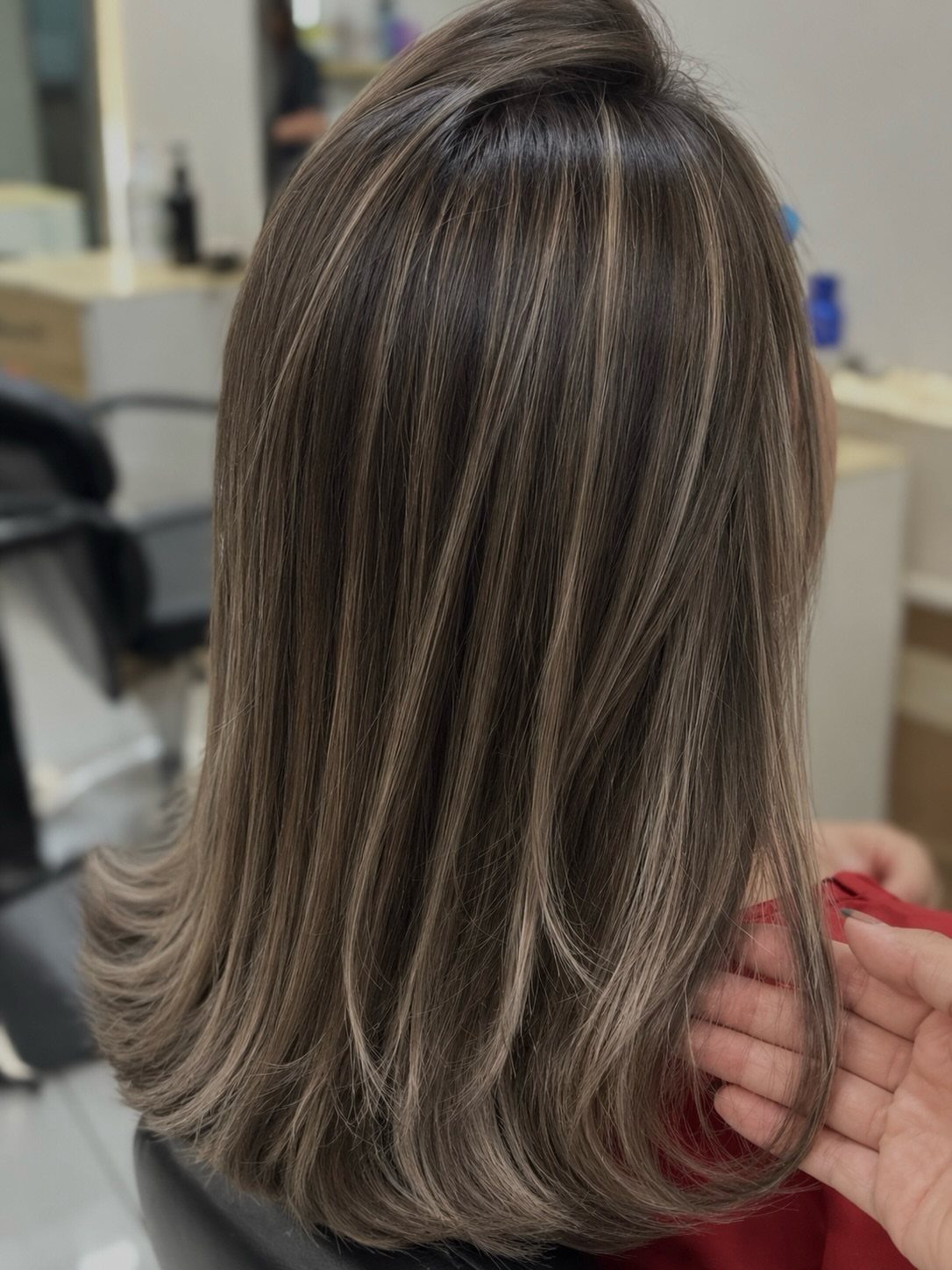 Long brown hair with blended blonde and ash-brown balayage highlights in a salon