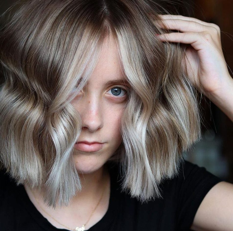 Short blonde bob with dark roots and contrasting light streaks around the face