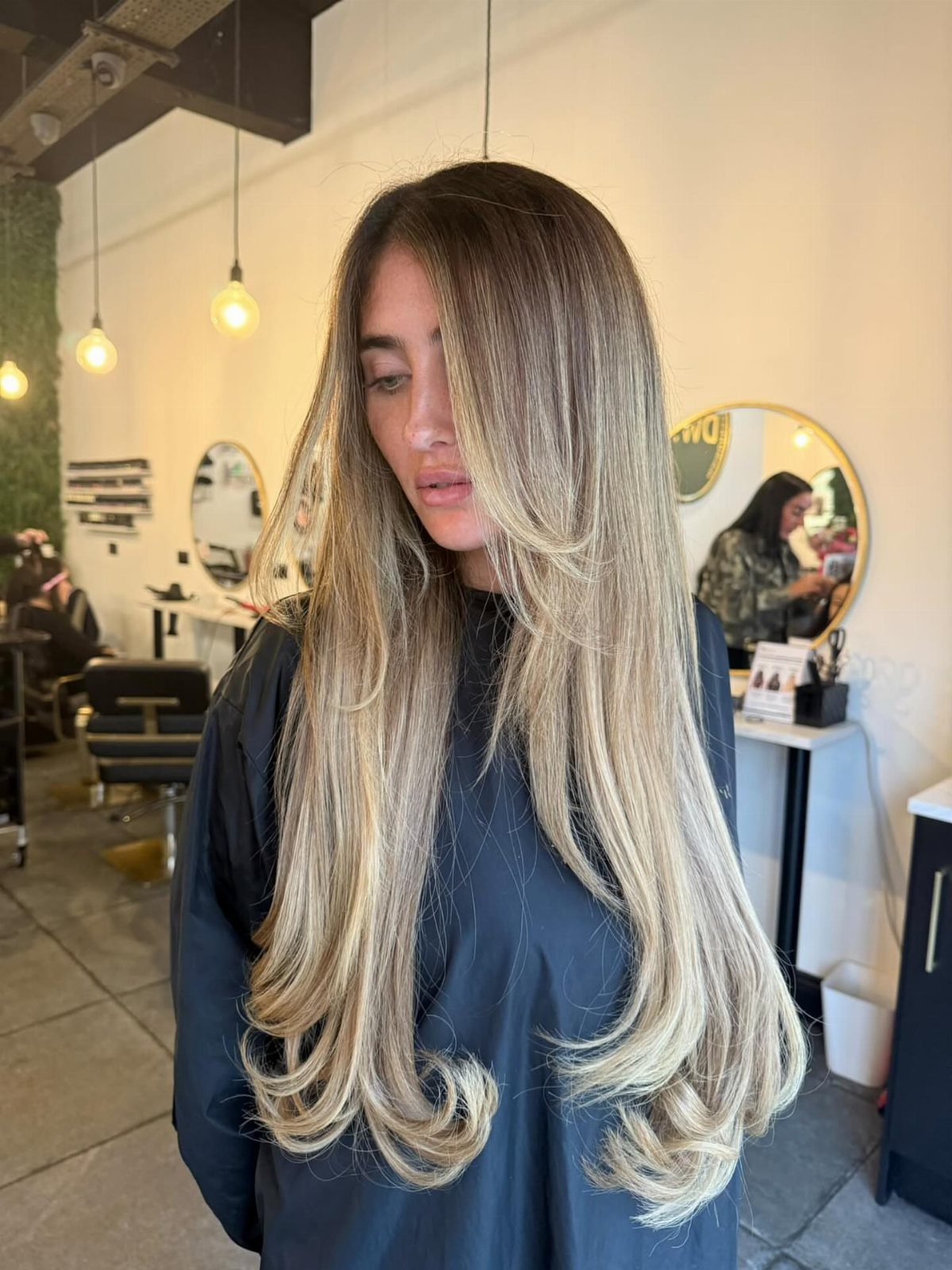 Long brown-blonde hair with bright face-framing highlights in a salon