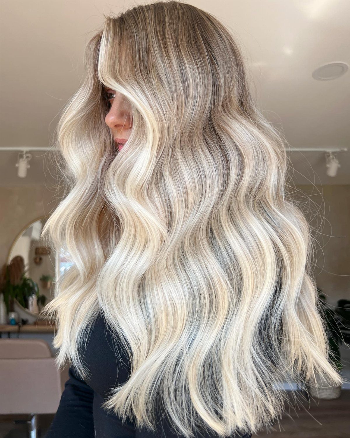 Long wavy blonde hair with darker roots and softly blended pale highlights