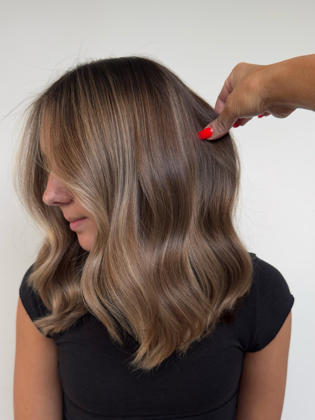 Shoulder-length brown waves show fine blonde highlights framing the face