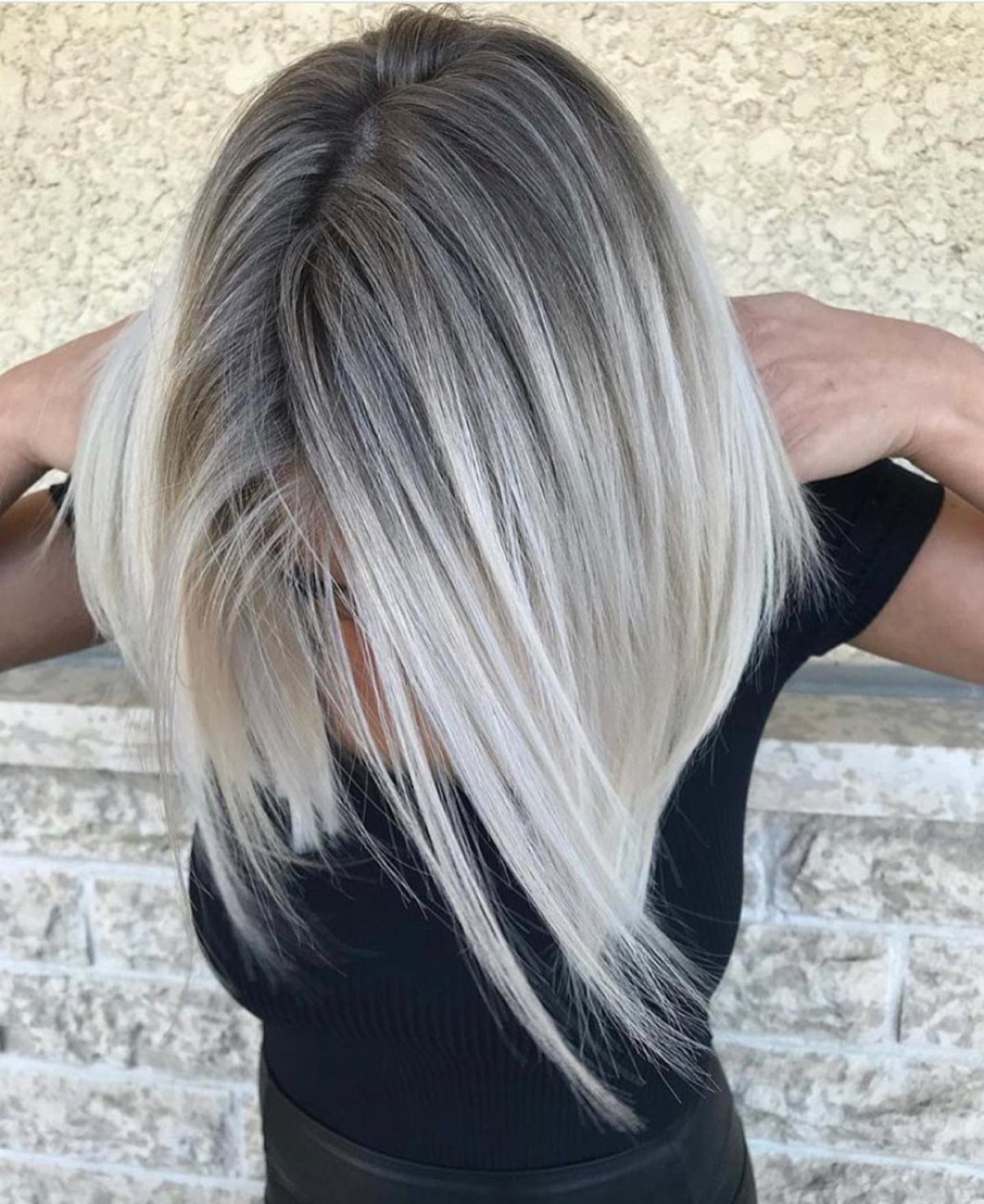 Long hair fades from dark ash-brown roots to icy white-blonde ends