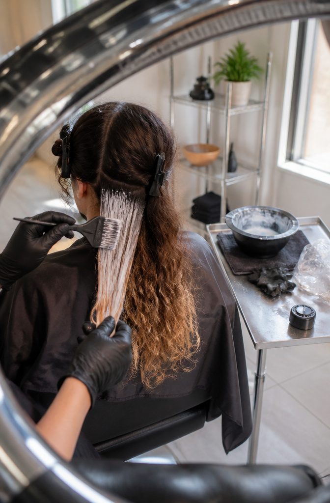 Sectioned dark curls with lightener on mid-lengths and ends and bare roots
