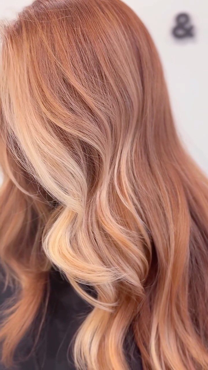 Wavy strawberry blonde hair featuring layered copper and light blonde highlights