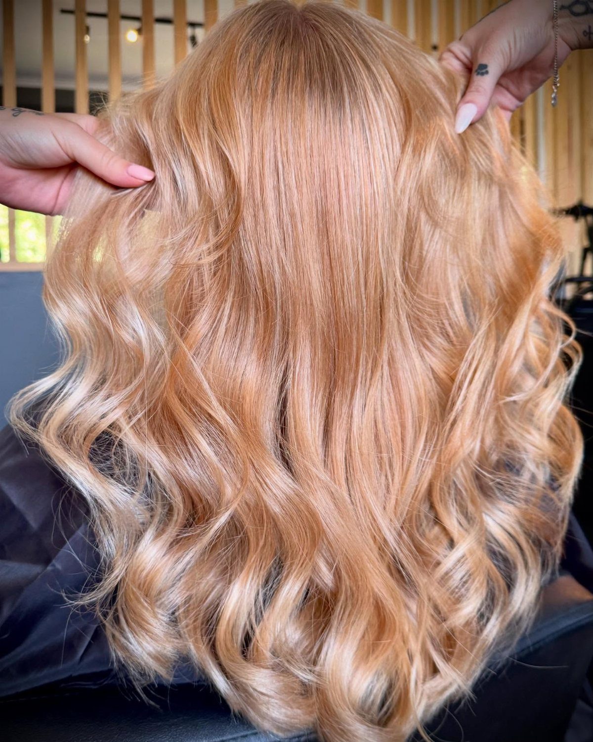 Creamy strawberry-blonde curls are lifted apart near the crown by two hands