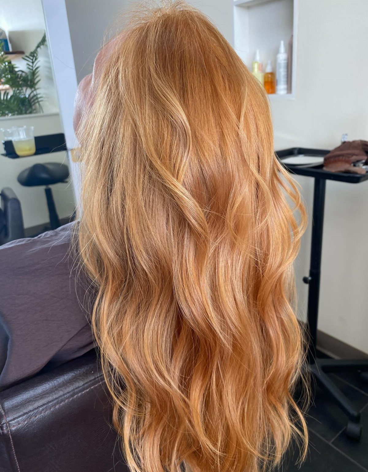 Long wavy strawberry-blonde hair with warm golden copper tones in a salon