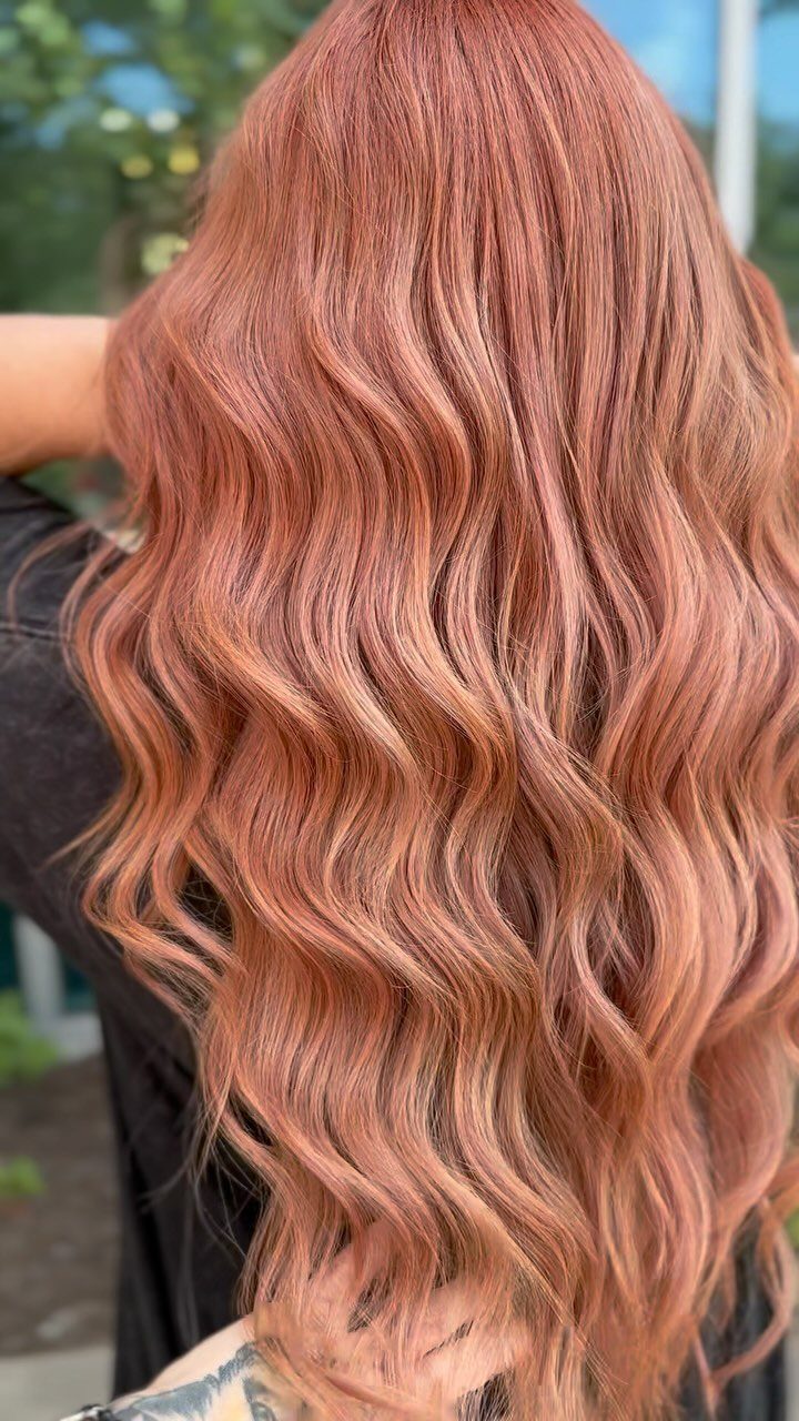 Wavy pastel peach blonde hair with darker roots shown from behind