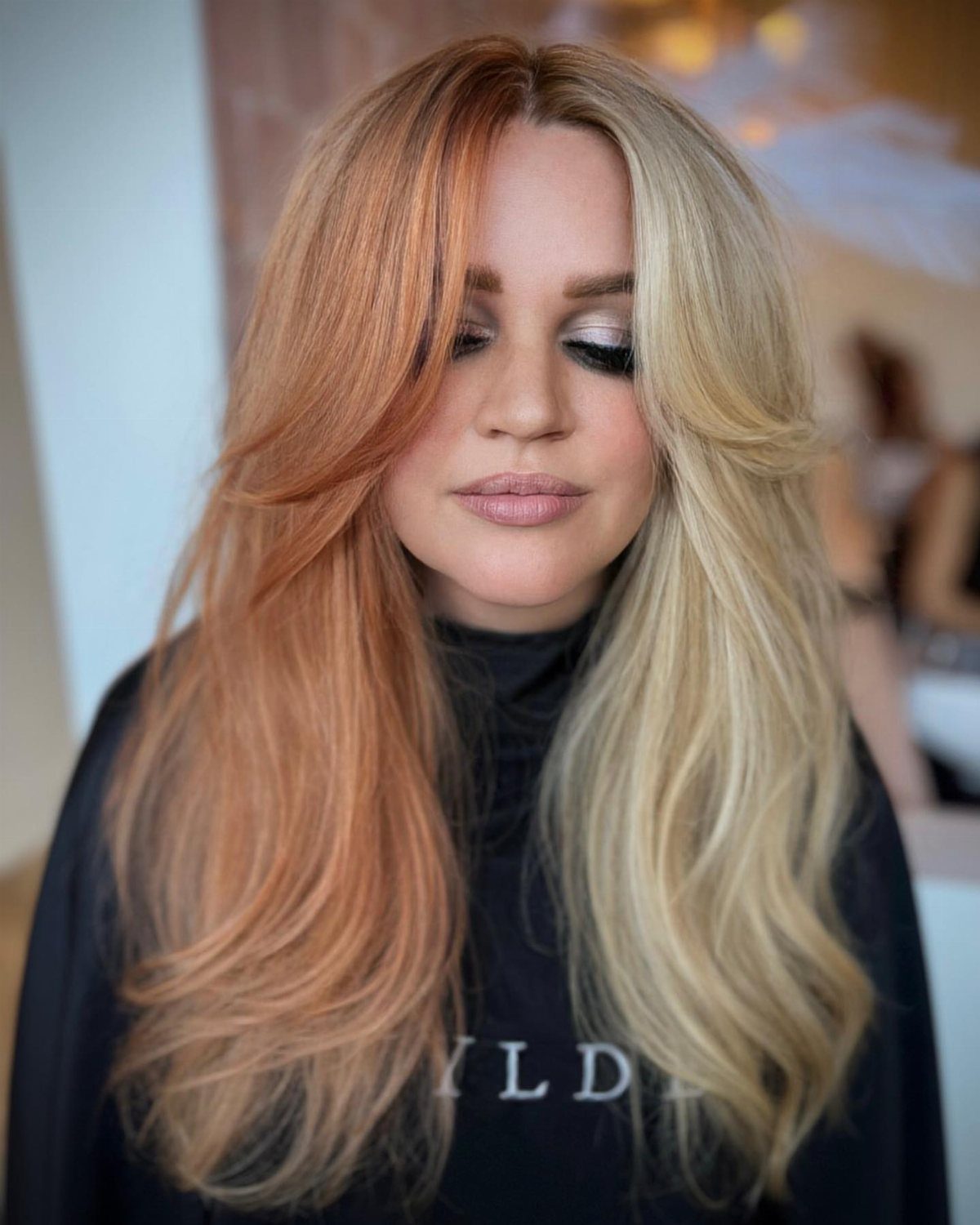 Woman displaying long layered hair in strawberry blonde and pale blonde