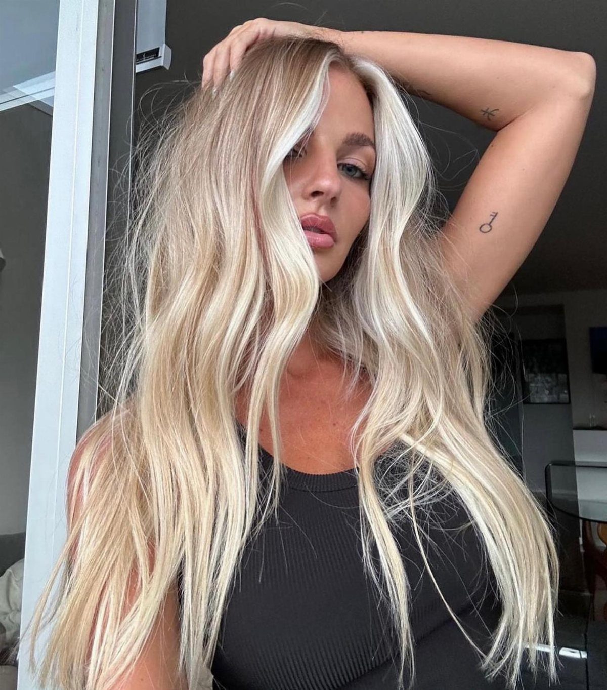 Woman showing long blonde waves with bright face-framing pieces and darker roots