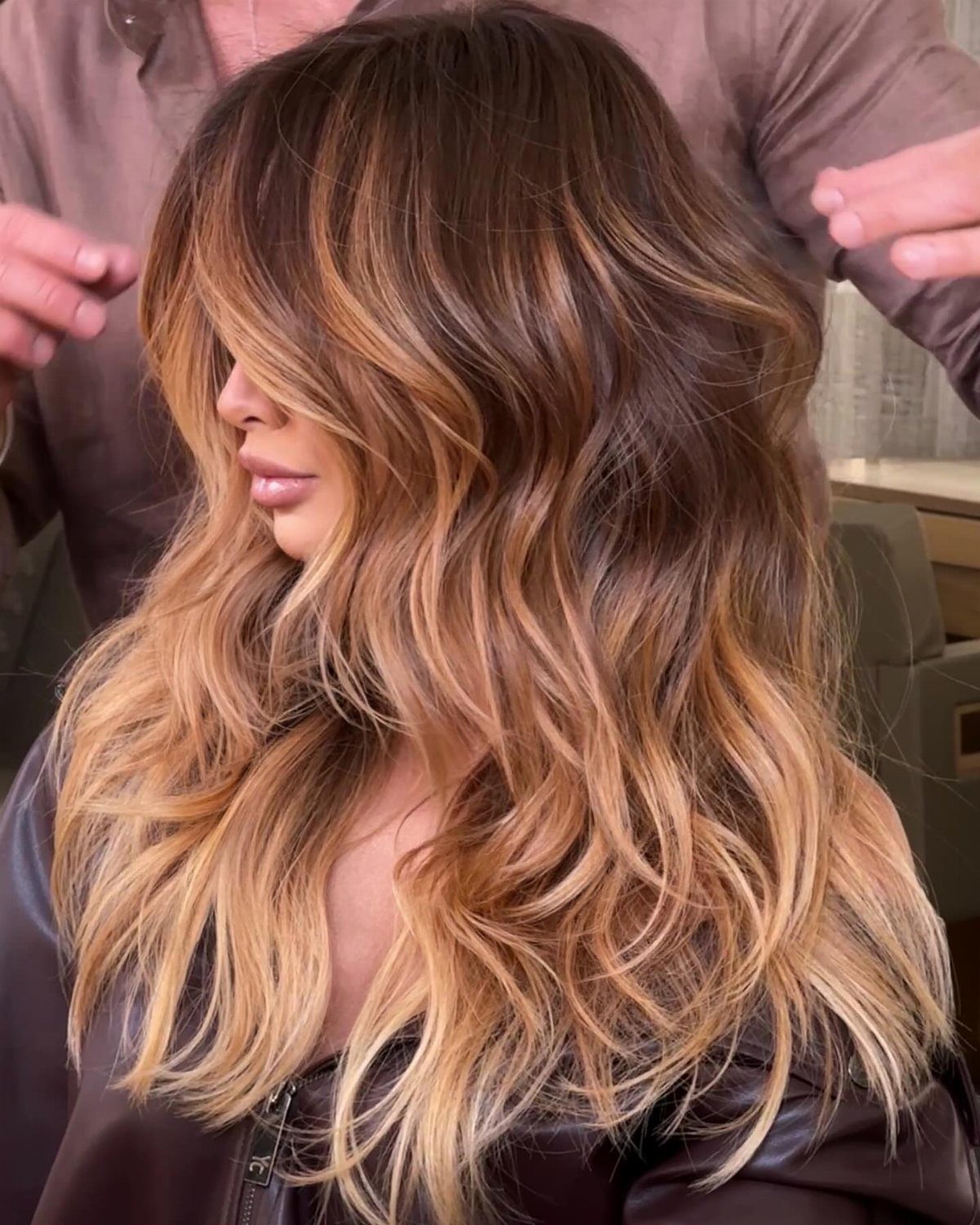 Long wavy caramel balayage hair blends dark roots with golden blonde lengths