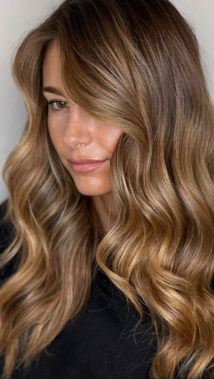 Woman with long wavy brown hair and dimensional golden blonde balayage