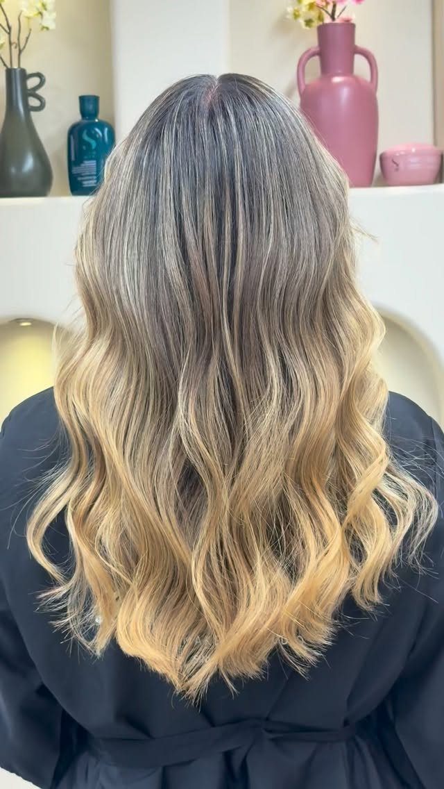 Wavy hair fades from dark roots to golden blonde ends