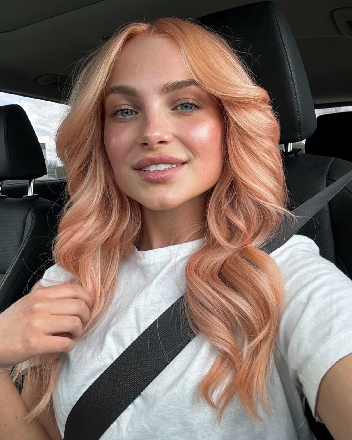 Woman with long peachy golden blonde waves sitting in a car