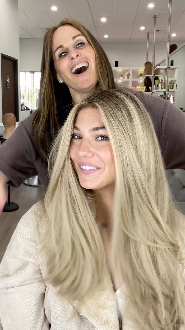 Woman with long platinum blonde hair sits smiling in a salon