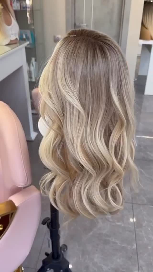 Long wavy light blonde hair with dark roots displayed on a salon mannequin