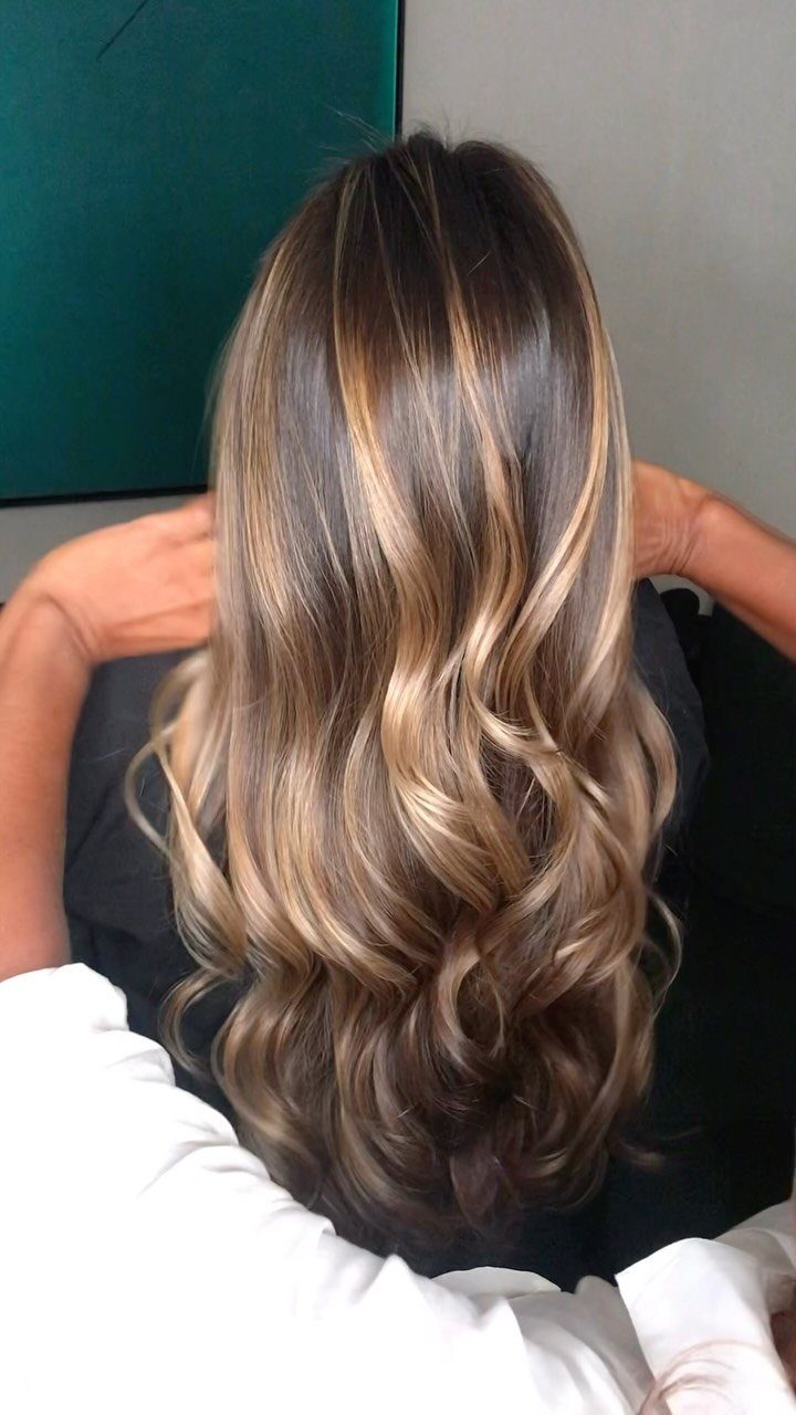 Long wavy medium brown hair with subtle warm blonde balayage highlights