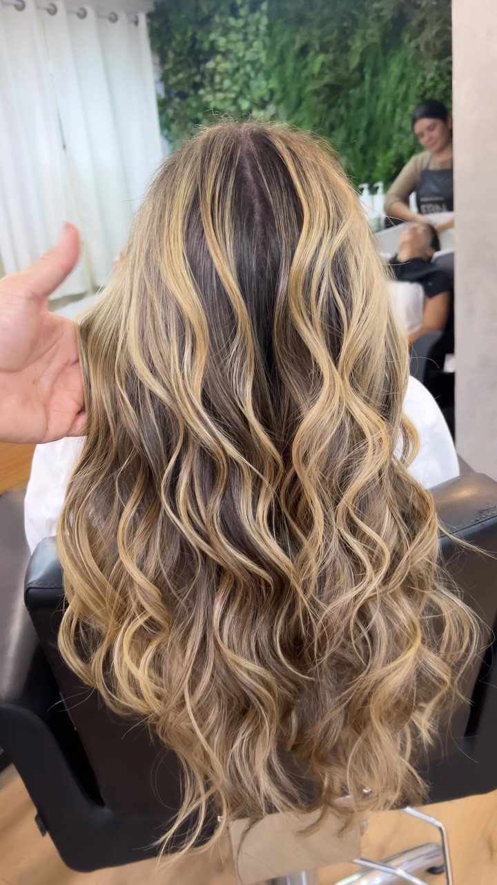 Long wavy blonde balayage hair with darker roots and blended golden highlights