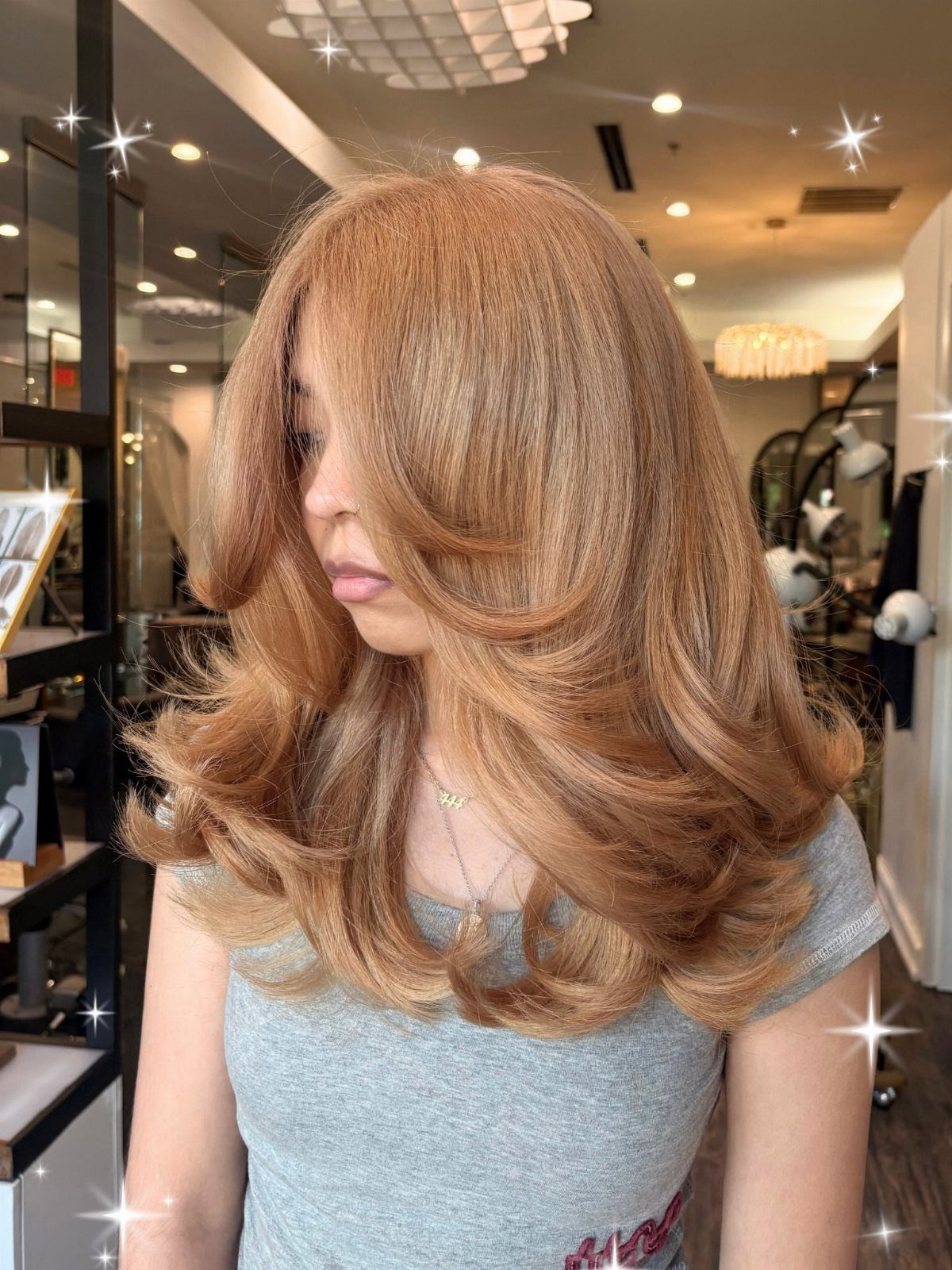 Woman displaying full warm honey-blonde hair in voluminous layered salon curls