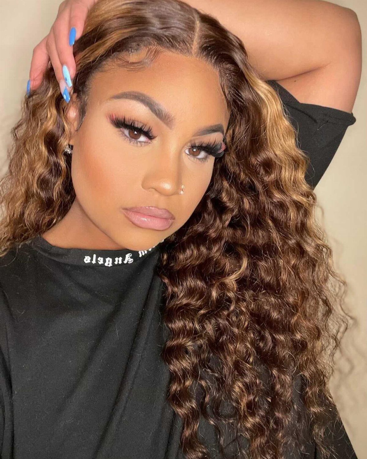 Woman with long brown curls and honey blonde highlights framing her hairline