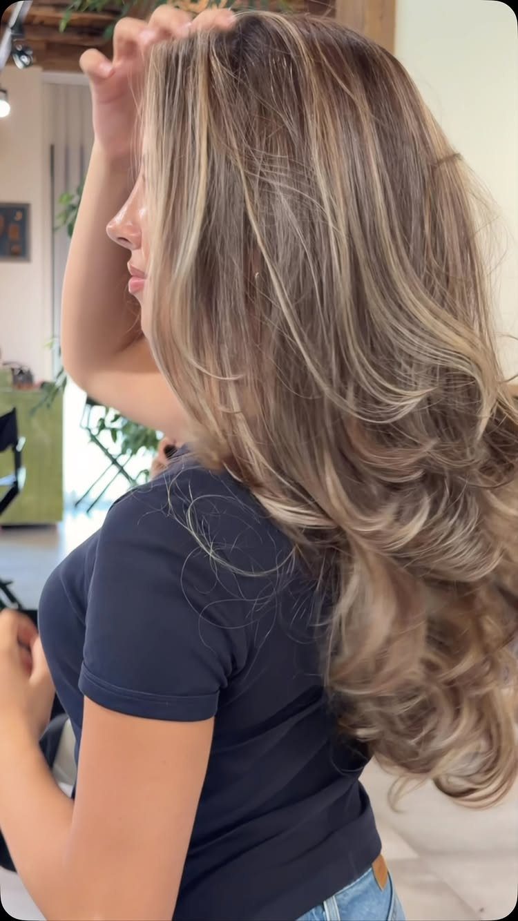 Wavy sandy blonde hair with bright, sun-kissed highlights in a salon