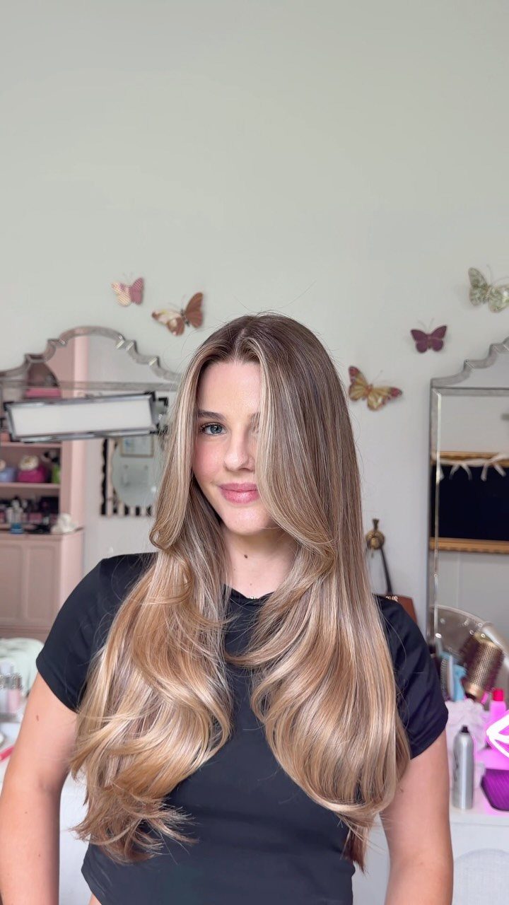 Woman with long, curled dark blonde hair in warm honey and caramel tones