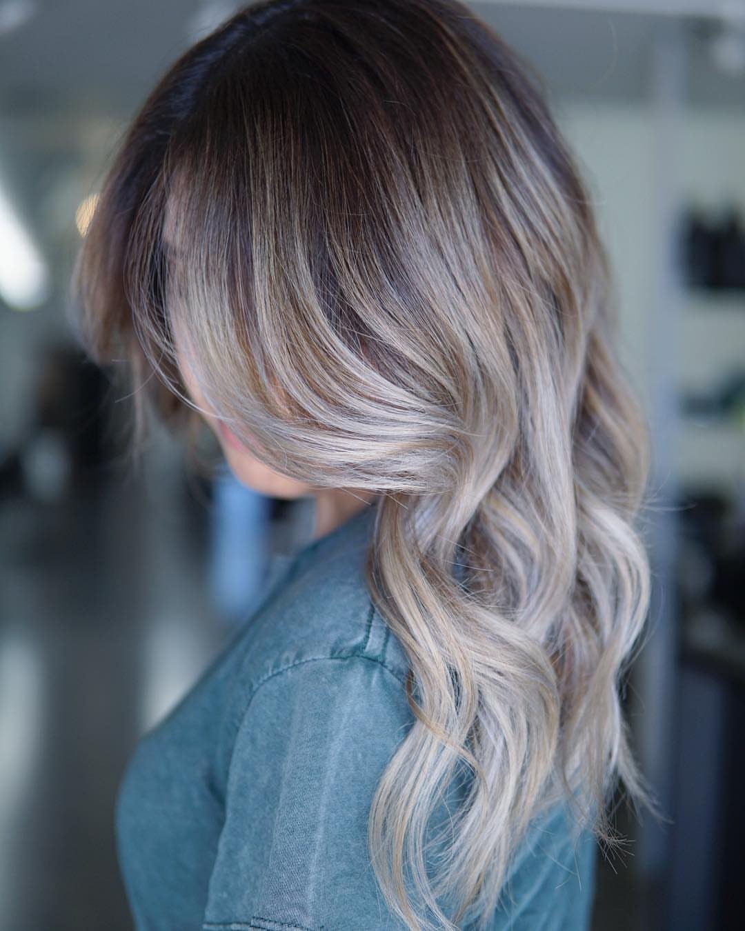 Long wavy hair with dark roots blending into honey-blonde lengths