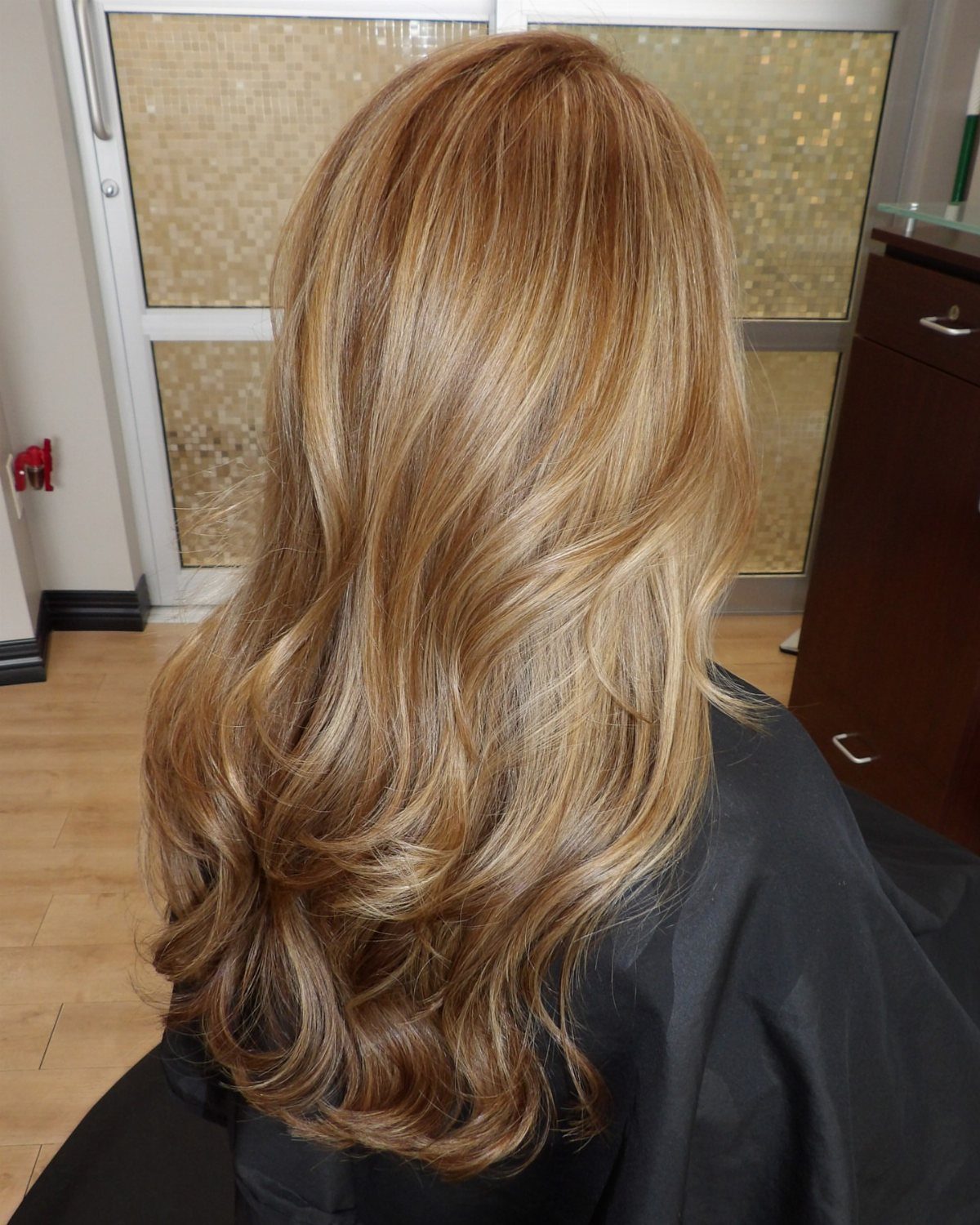 Long golden honey blonde hair styled in loose, layered curls