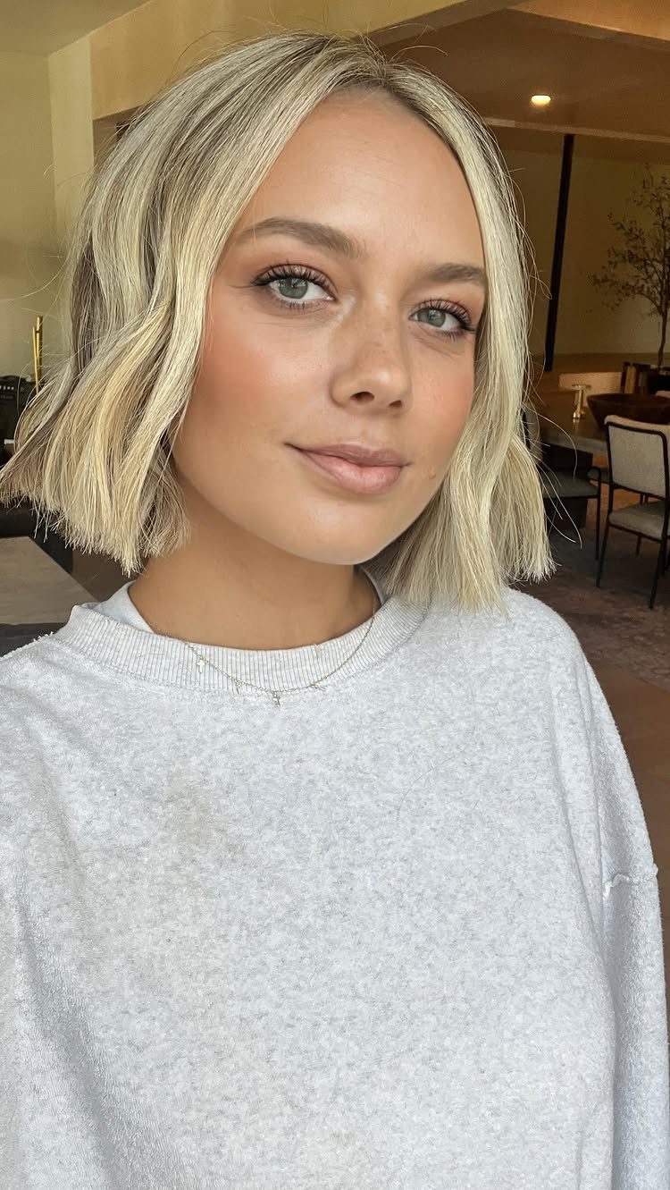 Woman posing with a chin-length honey blonde bob and darker roots