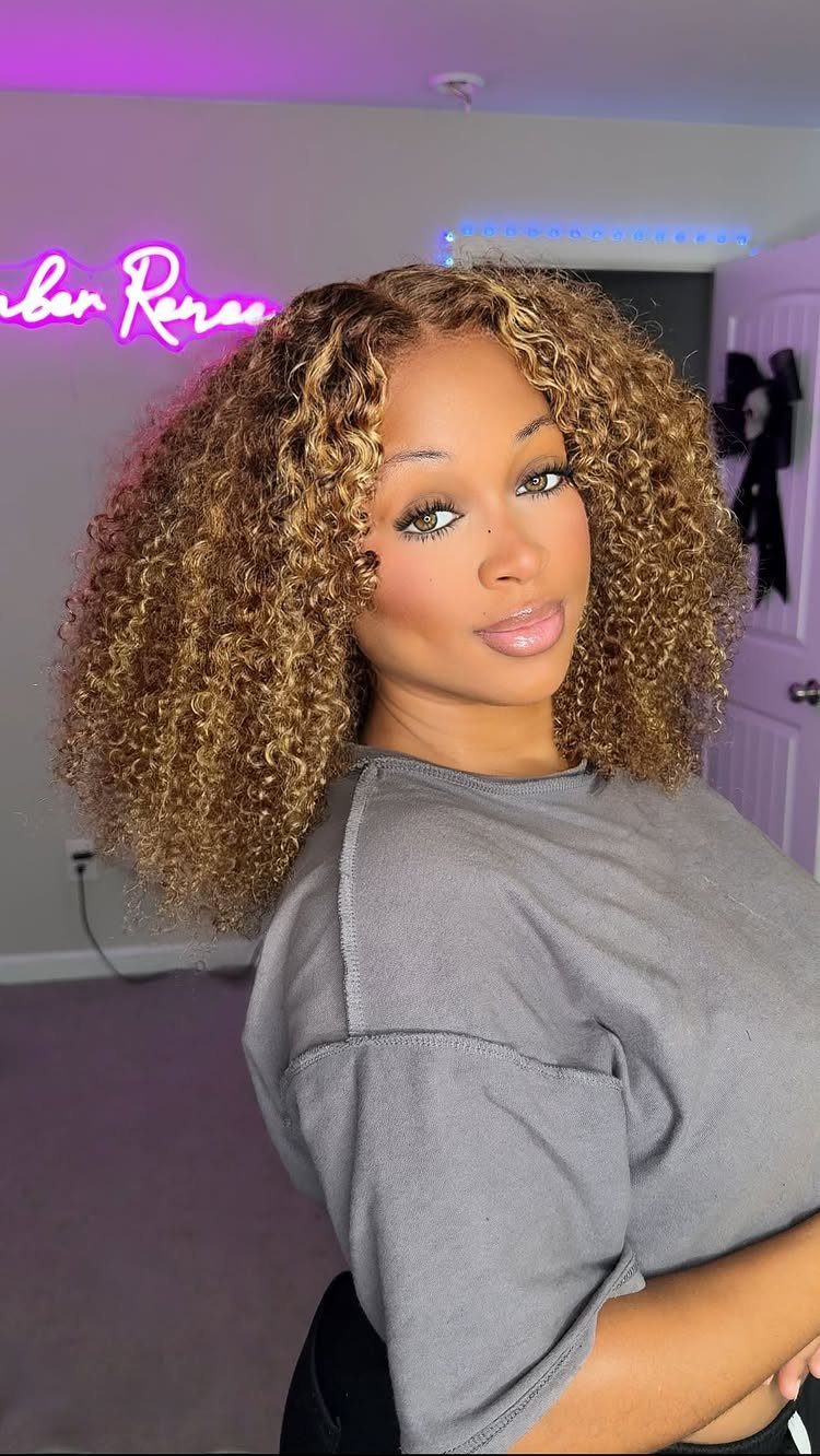 Woman with a shoulder-length honey-blonde curly bob posing in a salon