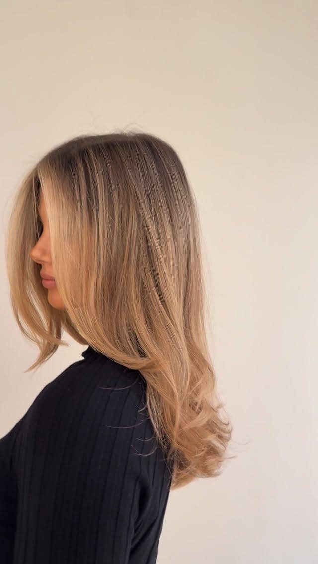 Woman with long brown-to-honey-blonde hair styled in soft curls