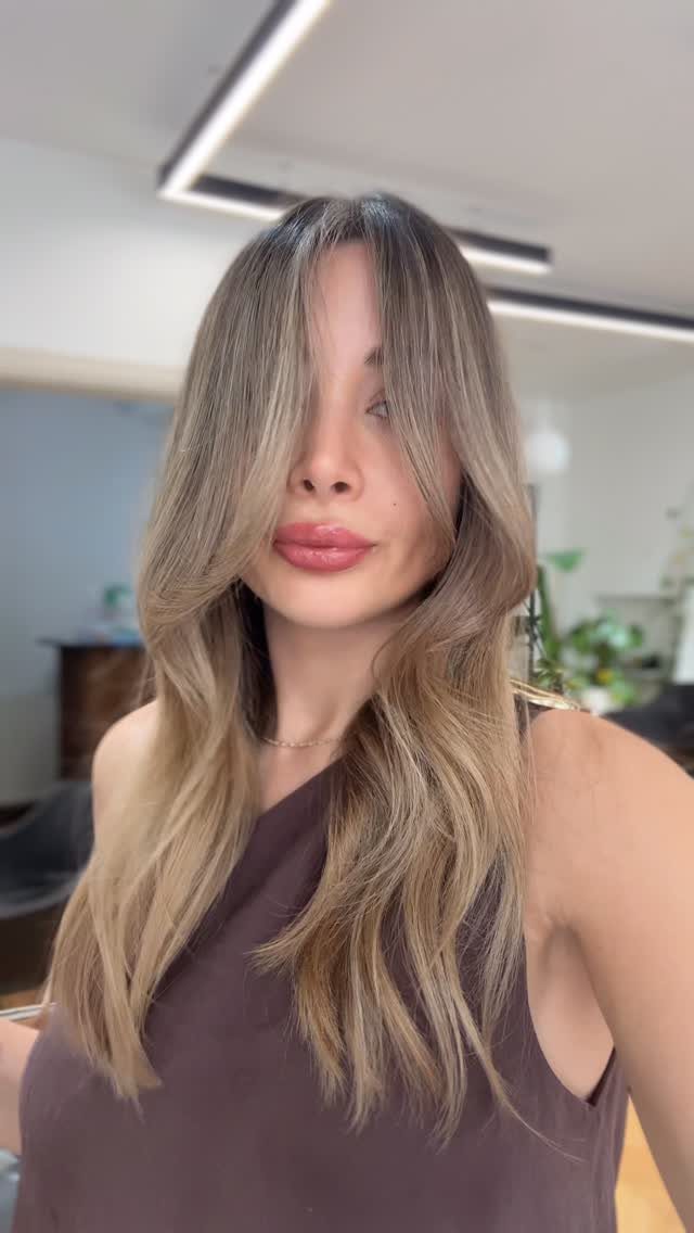 Woman with long, wavy light honey-blonde hair and darker roots