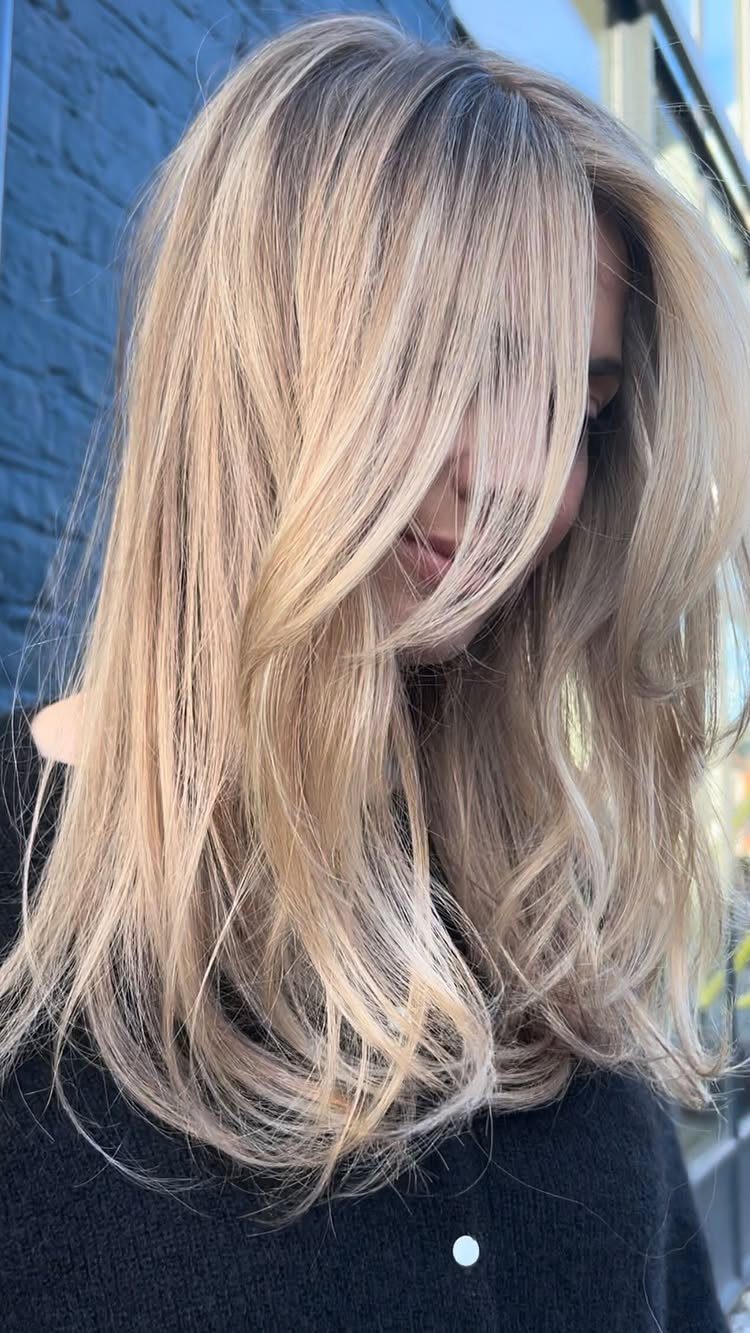 Long layered pale honey blonde hair with a side-swept fringe
