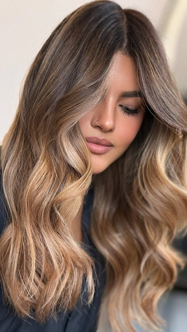 Woman with long wavy hair in warm honey-blonde and caramel tones