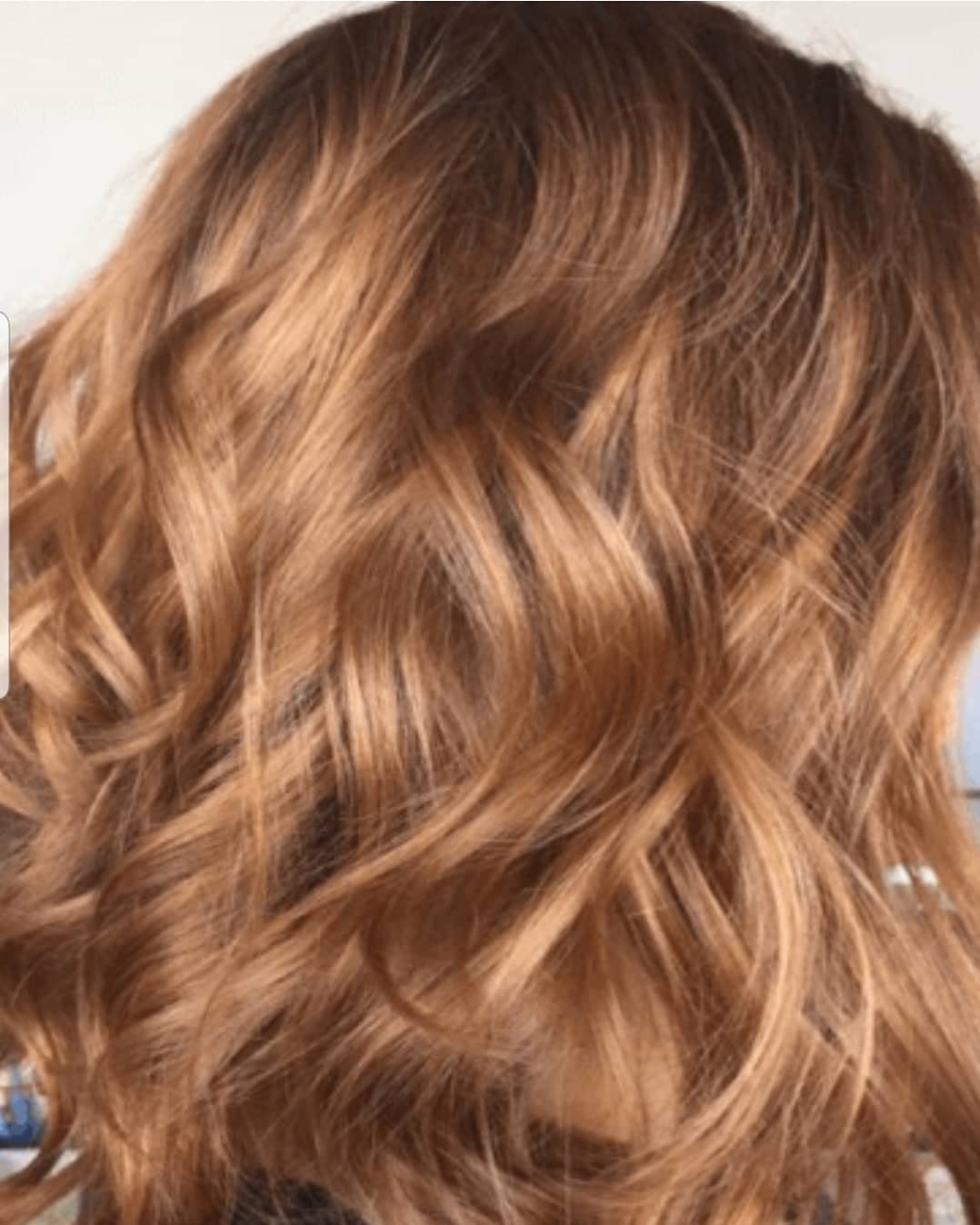 Wavy honey-brown hair with glowing coppery amber highlights