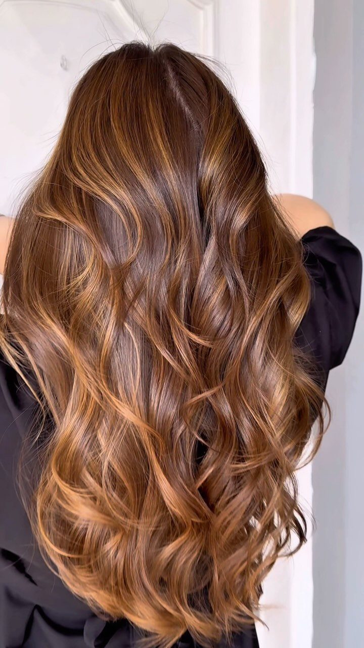 Long wavy brunette hair blended with warm caramel and butterscotch tones