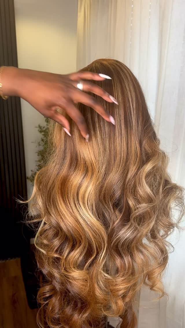 Honey-brown hair with golden highlights styled in glossy waves