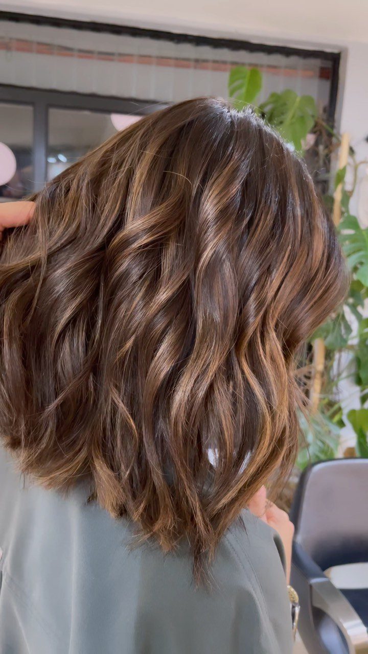 Long wavy brown hair with fine golden highlights in a salon