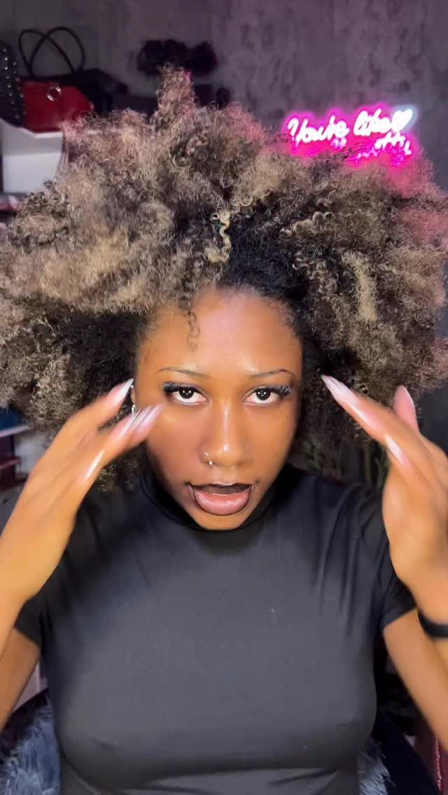Woman displaying honey-brown highlights throughout voluminous black natural hair