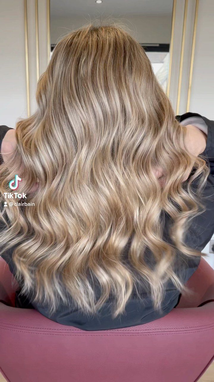 Long honey-brown waves with shimmering blonde highlights in a salon
