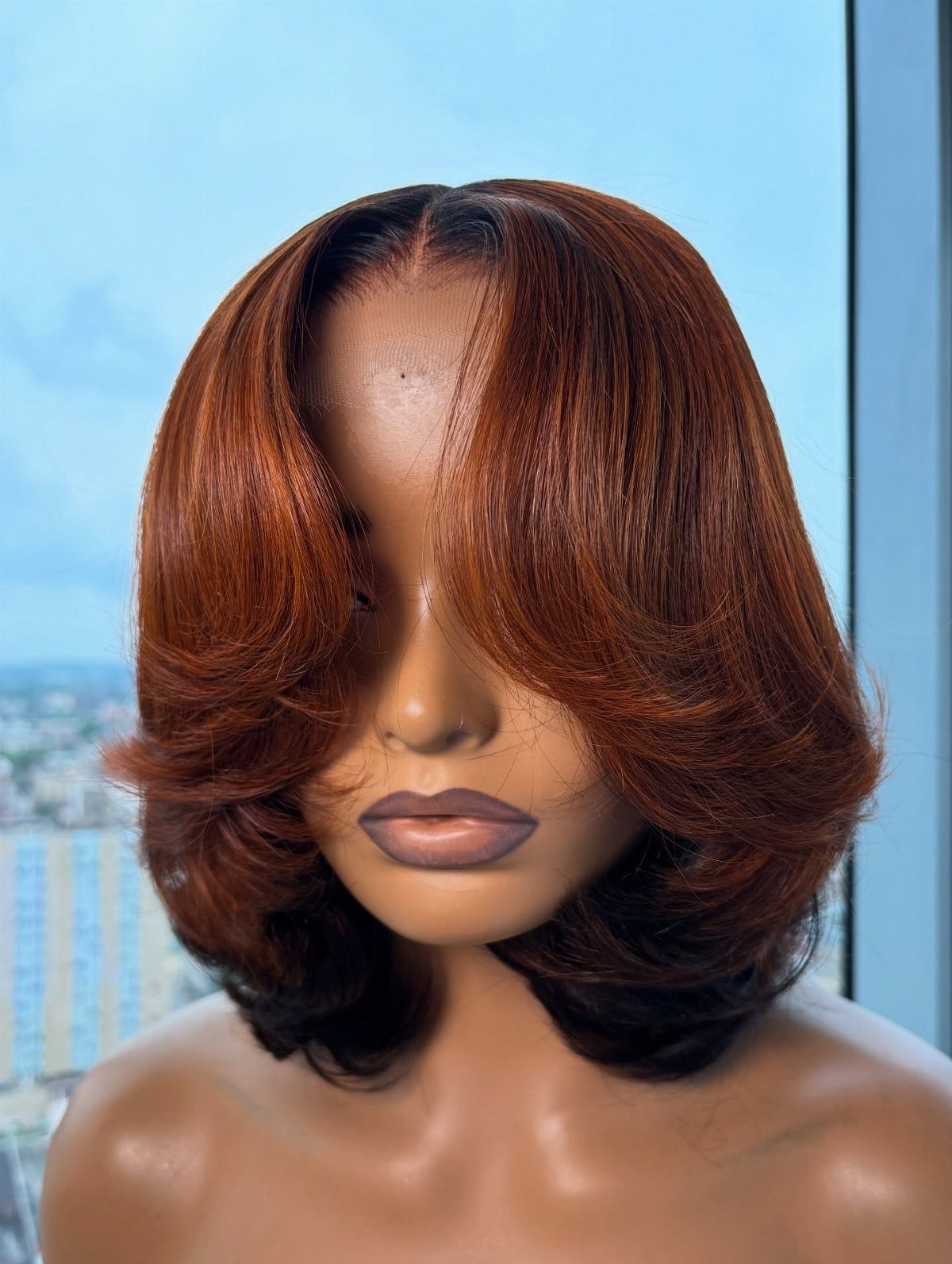 Mannequin displaying a warm honey-brown bob with voluminous curled ends