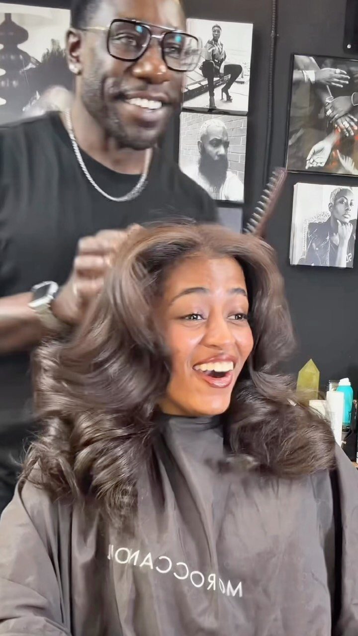 Woman smiling with voluminous, curled medium brown hair in a salon chair